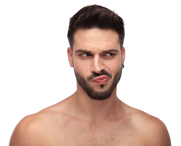 goofy undressed guy with beard looking away curious - Фото, зображення