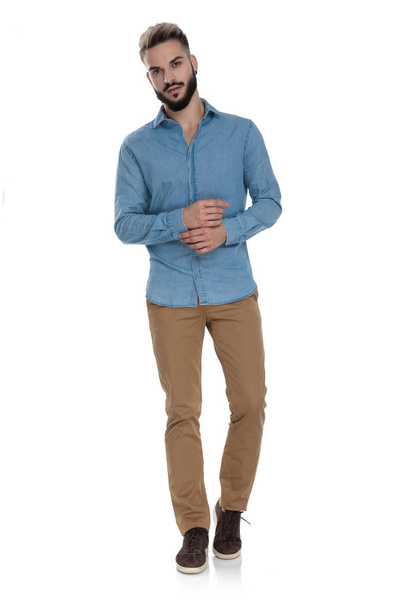 staande student in blauwe jas shirt aanpassen van zijn mouw - Foto, afbeelding