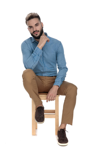 business student sitting relaxed and thinking with hand at chin - Photo, image