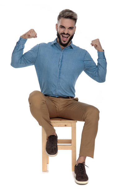 muž v džínách s modrou košilí a ukazující svaly - Fotografie, Obrázek