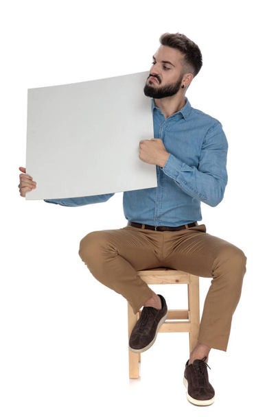 seated arrogant man recommending a blank billboard - Foto, imagen
