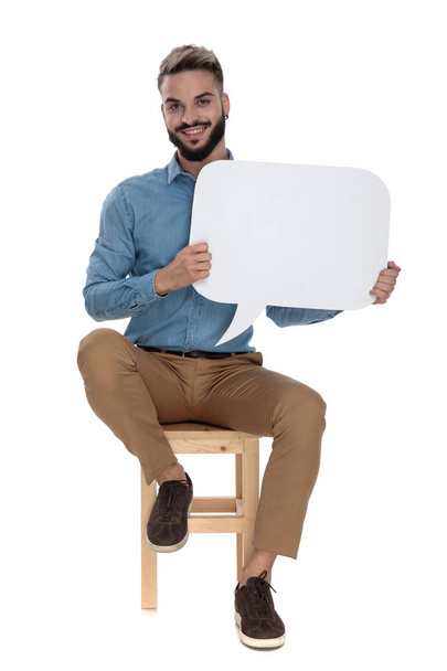 Entspannter Mann sitzt mit leerer Nachrichtenblase in der Hand - Foto, Bild