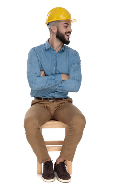 Casual mężczyzna z żółtym kask siedzący z zagiętymi ramionami - Zdjęcie, obraz