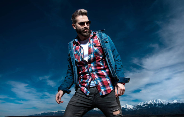 dramatic man in jeans clothes and sunglasses poses outdoor - Valokuva, kuva