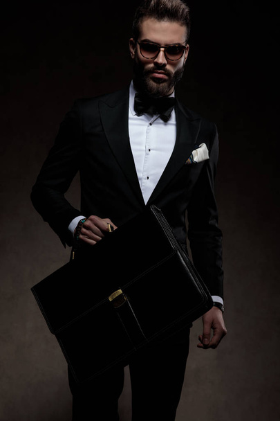 cool young man in tuxedo  holding briefcase and walking  - Photo, Image