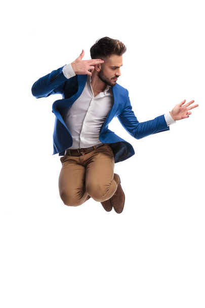 fashion man jumping and pointing pistol fingers to head  - Photo, Image