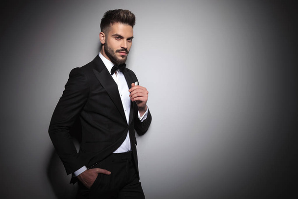 handsome young guy in black tuxedo holding hand in pocket - Photo, Image