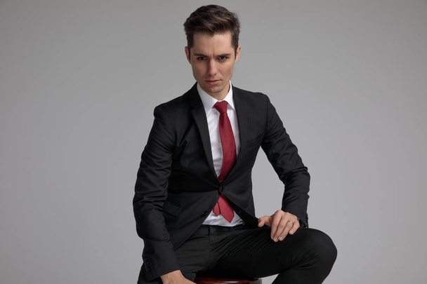serious elegant guy sitting with hands on legs - Photo, image