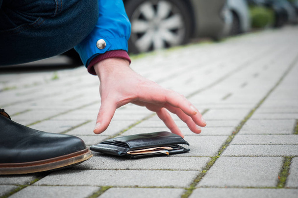 Человек потерял кожаный бумажник с деньгами на улице
 - Фото, изображение