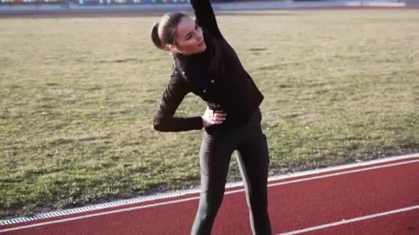 Beautiful young woman at the stadium performs different fitness exercises. - Záběry, video