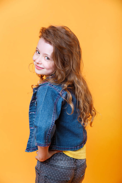 Portrait of beautiful happy little curly girl on orange background - Foto, Imagem