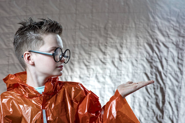 a boy in a bright orange raincoat and round glasses on his palm holding a painted cloud - Foto, immagini