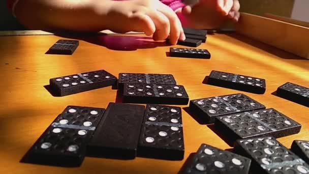 Enseñar a los niños a jugar al juego de dominó sobre un fondo de madera, principio dominó, el niño está jugando
. - Imágenes, Vídeo