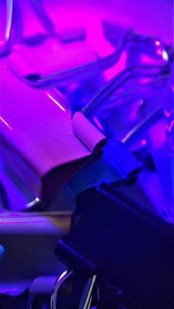 Colored paper clips under the rays of ultraviolet macro close up for background - Photo, Image