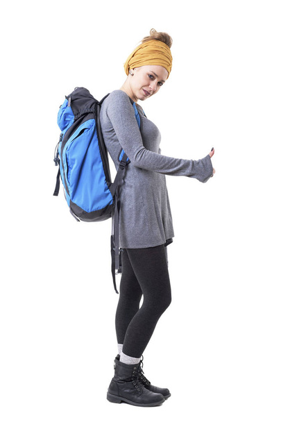 Cool backpacker young hipster woman with rucksack hitchhiking and looking at camera. Full body isolated on white background.  - Photo, Image