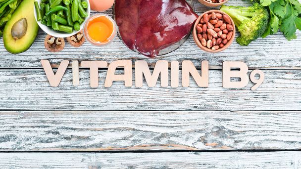 Foods that contain natural vitamin B9: Liver, avocado, broccoli, spinach, parsley, beans, nuts, on a white wooden background. Top view. - Foto, imagen