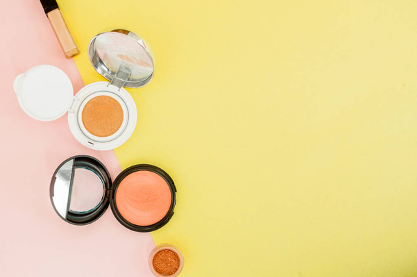Make up products spilling on to a bright yellow and pink background with copy space - Foto, Imagen