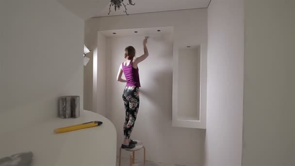 Σκηνή επισκευής σπιτιού. Όμορφη γυναίκα γυαλίζει τοίχο με εργαλείο λείανσης σε εσωτερικούς χώρους. - Πλάνα, βίντεο