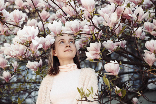 Giovane bella ragazza rilassarsi in un bellissimo giardino. Magnolia rosa fantastica
 - Foto, immagini