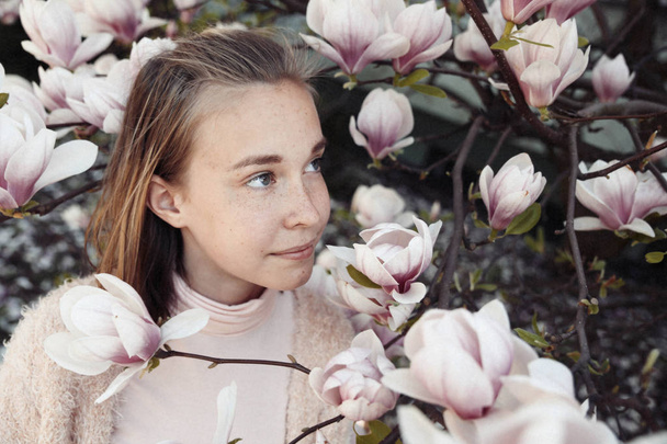 Young beautiful girl relax in beautiful garden. Fantastic pink Magnolia - 写真・画像