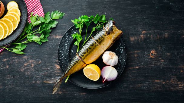 Smoked fish On a black wooden background. Top view. Free space for your text. - Foto, Imagen