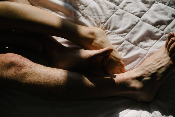 Feet of man and woman in bed close-up - Фото, изображение