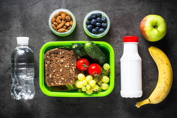 Boîte à lunch avec sandwich, fruits, légumes, eau
. - Photo, image