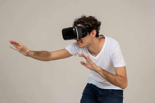 Amazed funny man using VR headset glasses touching and interacting with virtual reality world , feeling excited exploring and having fun in 360 VR simulation. Innovation and new technology concept. - Photo, image