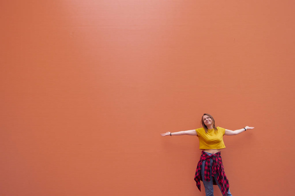 молодая стильная девушка стоит на коралловой стене и смотрит вверх
 - Фото, изображение