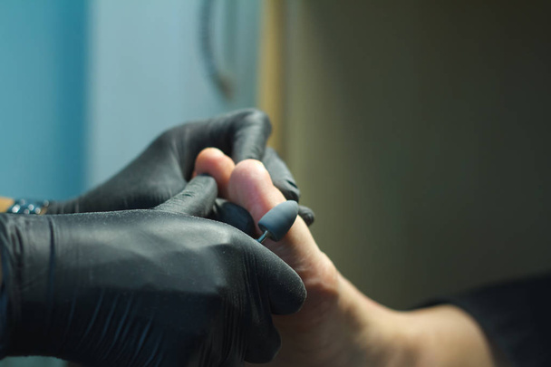 Close-up voet huidbehandeling proces. Handgeblauwde handen met een pedicure machine. - Foto, afbeelding