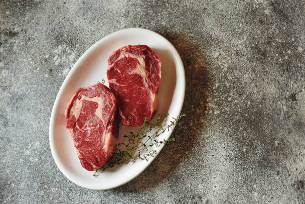 Steak cru juteux avec thym sur fond gris. Aliments sains biologiques. Vue du dessus
.  - Photo, image