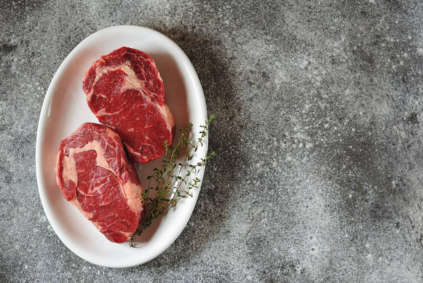 Sappige rauwe Steak met tijm op een grijze achtergrond. Biologisch gezond voedsel. Top View.  - Foto, afbeelding