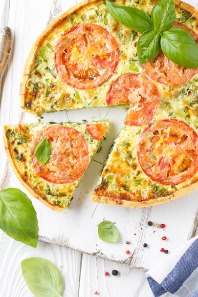Quiche with vegetables (squash, tomatoes, cheese, herbs, green o - 写真・画像