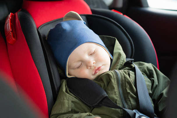 Close-up Kaukasische schattige baby jongen slapen in moderne autostoel. Kind reizen veiligheid op de weg. Veilige manier om veiligheidsgordels te reizen in een voertuig met jonge kinderen. Reis met peuter. - Foto, afbeelding