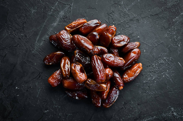 Dry date on a black background. Top view. Free space for your text. - Foto, afbeelding