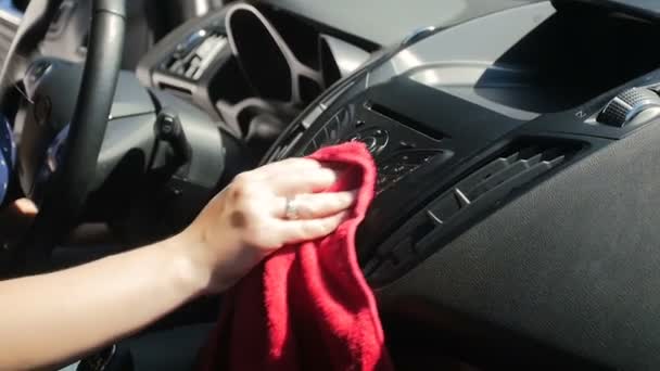 Zbliżenie wideo powolny ruch młodej kobiety czyszczenia jej deski rozdzielczej samochodu z kurzu i brudu z tkaniny z mikrofibry. Maszynista polerowanie tworzyw sztucznych we wnętrzu pojazdu - Materiał filmowy, wideo