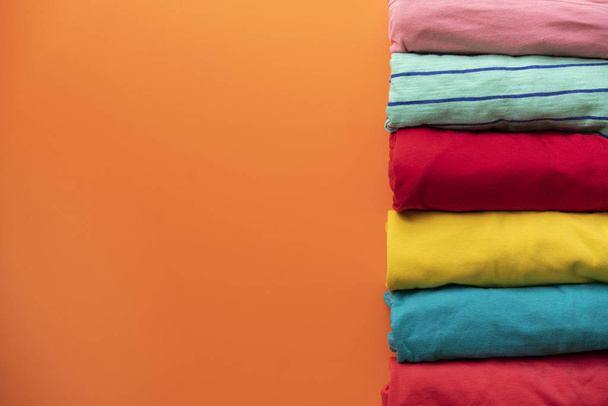 close up of rolled colorful clothes on orange background - Foto, Imagen