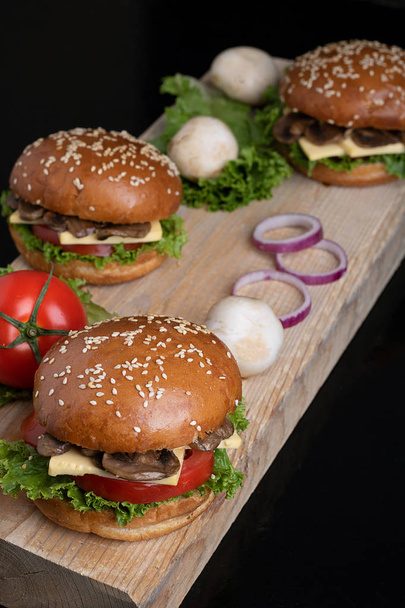 side view, highlight on tomato, backlight, mushroom burgers on the kitchen board - Foto, imagen