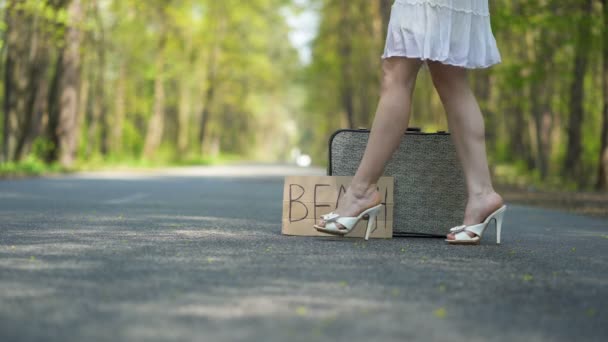4K. πόδια της γυναίκας σε ψηλά τακούνια παπούτσια κοντά ρετρό βαλίτσα με αφίσα παραλία - Πλάνα, βίντεο