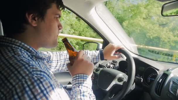 Sarhoş adamın araba kullanırken şişeden bira içerken ki yavaş çekim görüntüleri. Tehlikelidir ve trafik kazasına neden olabilir - Video, Çekim