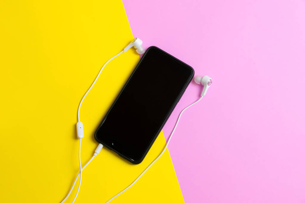 Smartphones et écouteurs Écoutez de la musique vintage sur fond jaune et rose
. - Photo, image