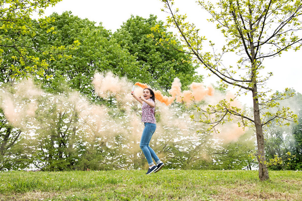 Heureuse jeune fille énergique avec une fusée éclairante de fumée
 - Photo, image