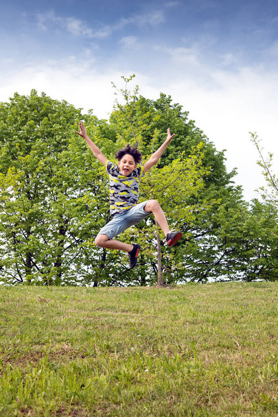 Agile young boy leaping high in the air - Фото, зображення