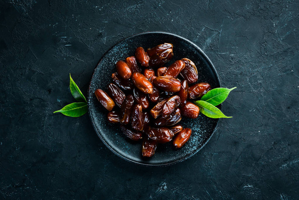 Dry date in a bowl on a black background. Dried fruit Top view. Free space for your text. - Φωτογραφία, εικόνα