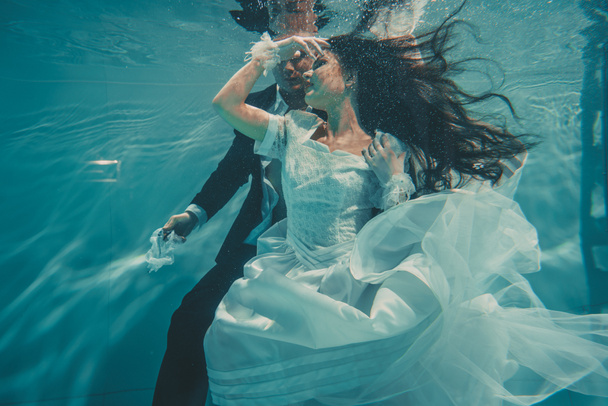 belo casal romântico de noiva e noivo após o casamento nadando suavemente sob a água e relaxar
 - Foto, Imagem