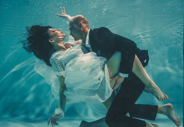 結婚式の後に新郎新婦の美しいロマンチックなカップルは、水の下で穏やかに泳ぎ、リラックス - 写真・画像