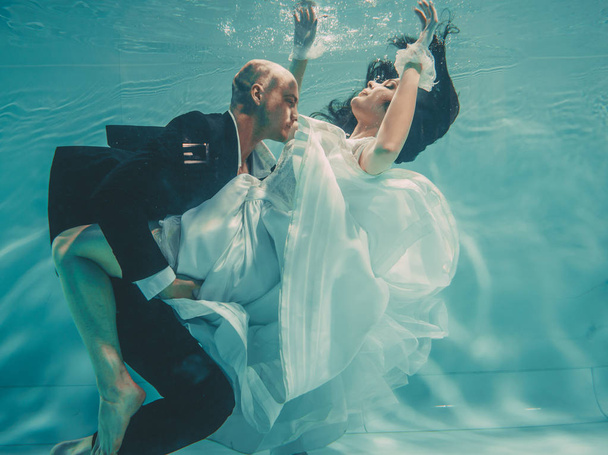 beautiful romantic couple of bride and groom after wedding swimming gently under water and relax - Fotografie, Obrázek