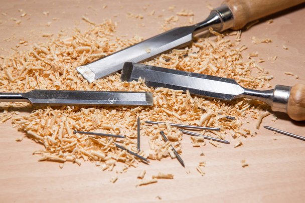 Стіл з зубчастими лопатями і стружками дерев'яної тирси і цвяхів робота майстерного теслі
. - Фото, зображення