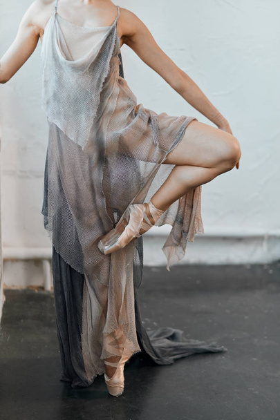 Ballet dancer with floating fabric flexing her leg aside, warm-up before dance - 写真・画像