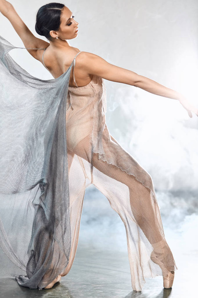 Flexibilní baletní tanečnice se protahuje v tmavém osvětleném studiu - Fotografie, Obrázek